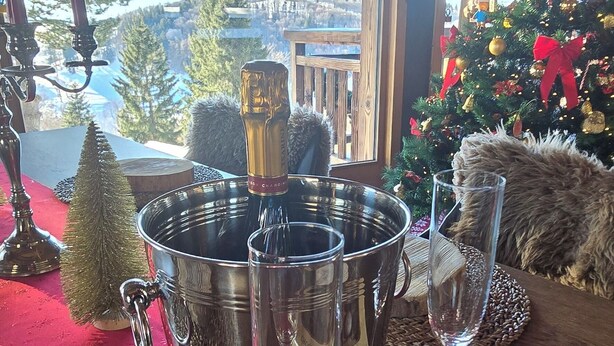 A table with a champagne bucket, two glasses, a small Christmas tree, and a box of chocolates. - Chalet lovers in Switzerland (Saint George)
