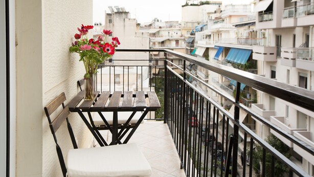 Varanda com banco de madeira e um vaso de flores.
