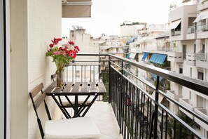 Een balkon met een houten bankje en een bloemenvaas.