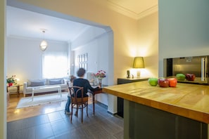 A modern kitchen with a wooden countertop, a refrigerator, and a dining area with a white table and chairs.