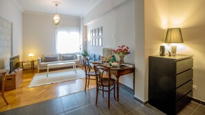 Uma sala de estar moderna com sofá, cadeiras, uma mesa de jantar e uma televisão.