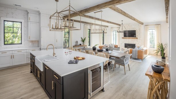 Eine geräumige Küche mit einer großen Kochinsel, Holzbalken und einem Kamin im Wohnbereich.
