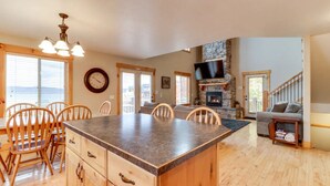 Una cocina amplia con una isla grande, sillas de madera, una mesa de comedor y una chimenea de piedra.