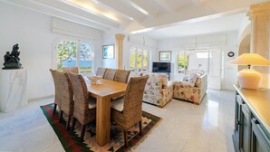 A spacious living area with a dining table, wicker chairs, a sofa, and a TV. - CAN RAMIS -  Seafront house with panoramic views. (Cielo de Bonaire)