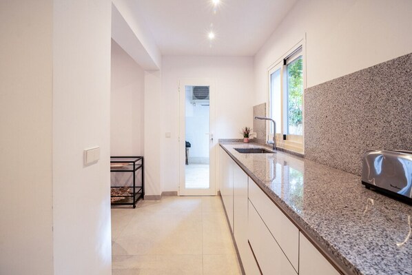 A modern kitchen with a granite countertop, a toaster, and a window providing natural light.