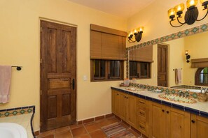 Un baño con puerta de madera, un espejo grande y un salpicadero de azulejos.