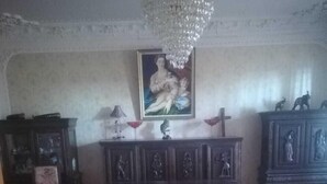 Una habitació amb un terra de fusta, un gran armari de fusta amb estàtues, una làmpada penjant i un quadre a la paret.