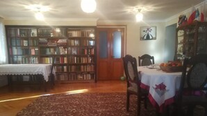 Una zona de menjador amb una taula preparada per a dues persones, una prestatgeria i una catifa amb un disseny.