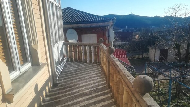Una escala de fusta amb barana que condueix a un edifici amb antenes satèl·lit.