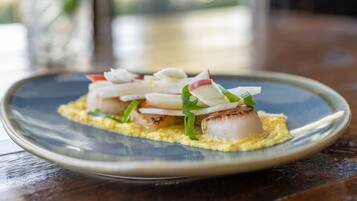 A plate of food with scallops, radishes, and green onions on a blue plate.