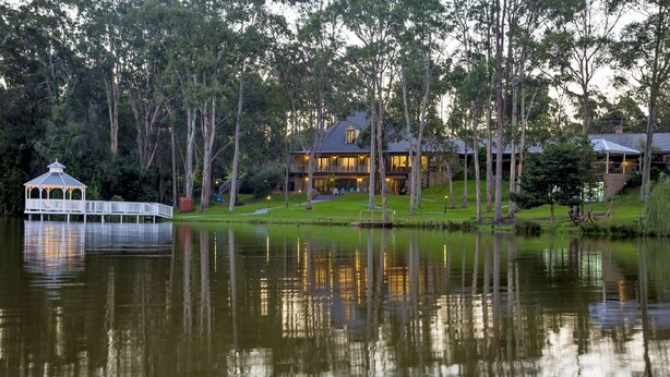 Una cabaña junto al lago con un porche, una casa grande y un muelle.
