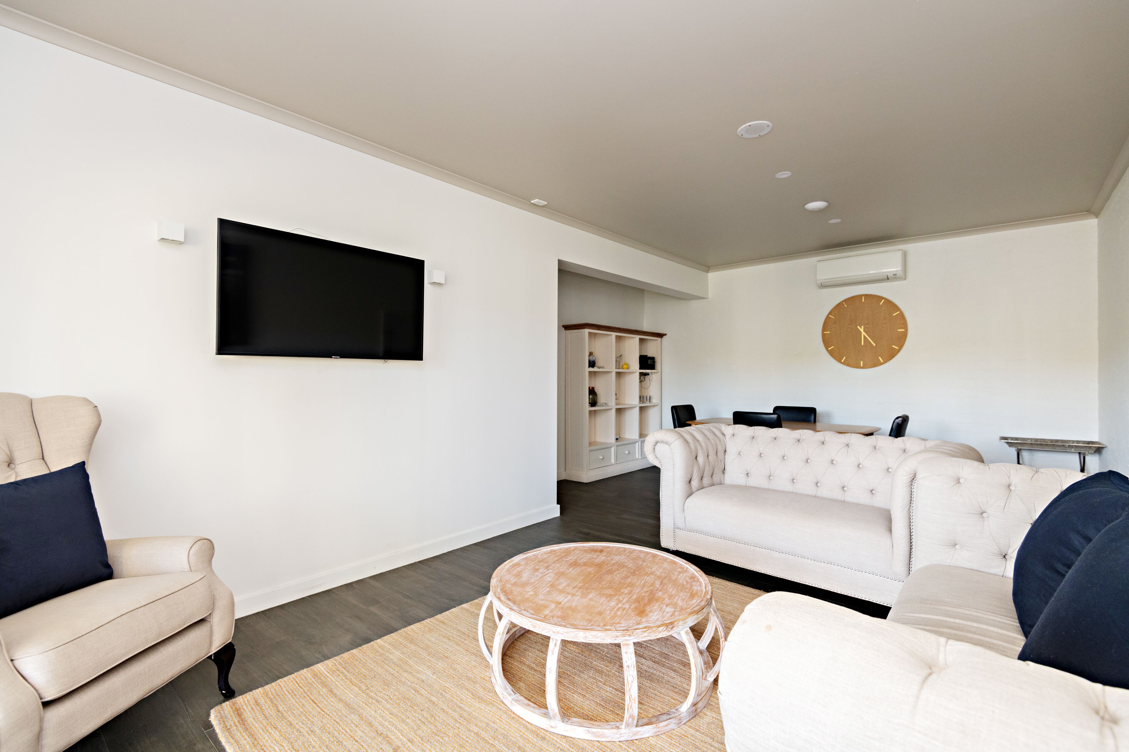A living room with a flat-screen TV, a round wooden coffee table, and a beige sofa.