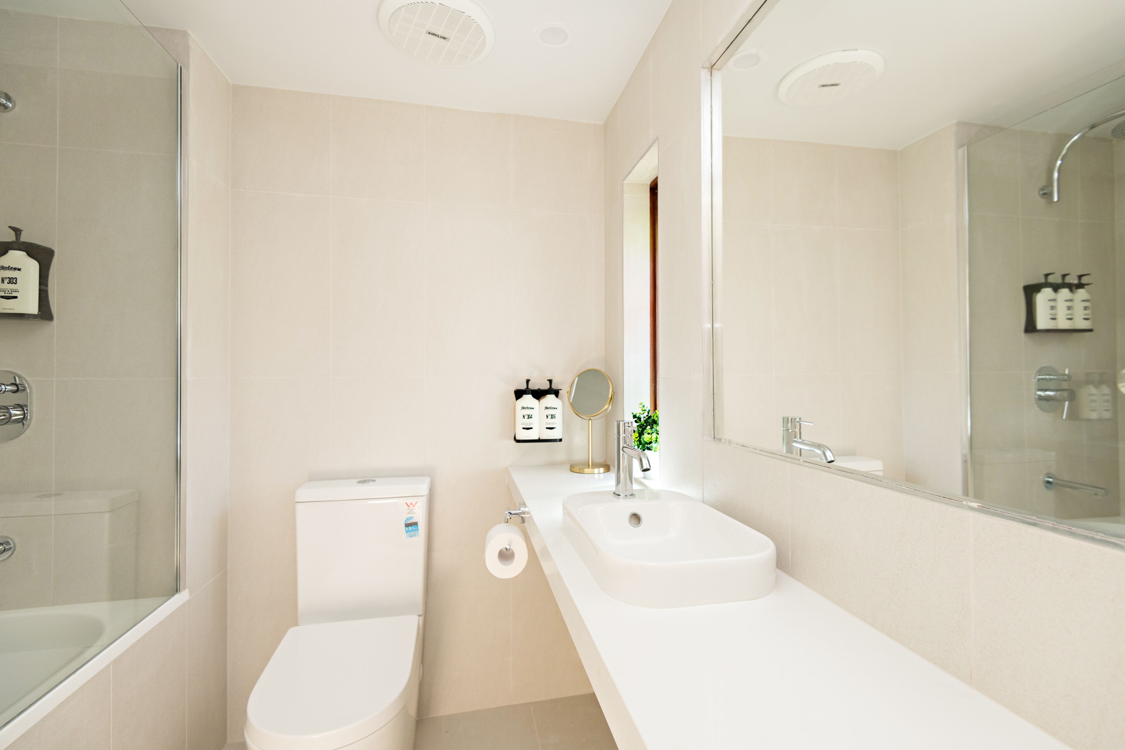 A modern bathroom with a glass shower enclosure, a toilet, a sink, and a large mirror.