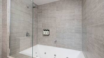 A modern bathroom with a glass-enclosed shower, a freestanding bathtub, and a wall-mounted soap dispenser.