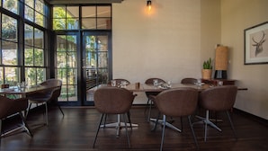 Comedor con una mesa lista para cuatro personas, rodeada de sillas, y un ventanal que ofrece vistas a zonas verdes.