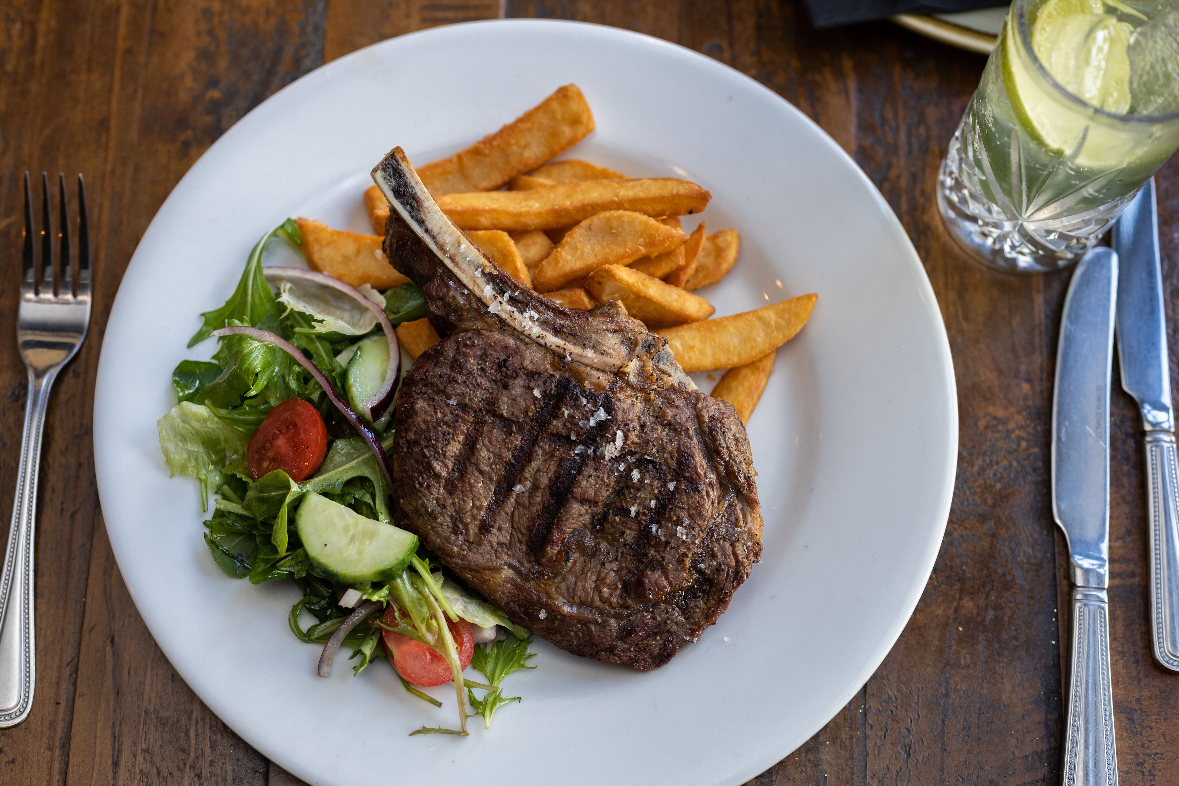A plate with a grilled steak, fries, and a salad.
