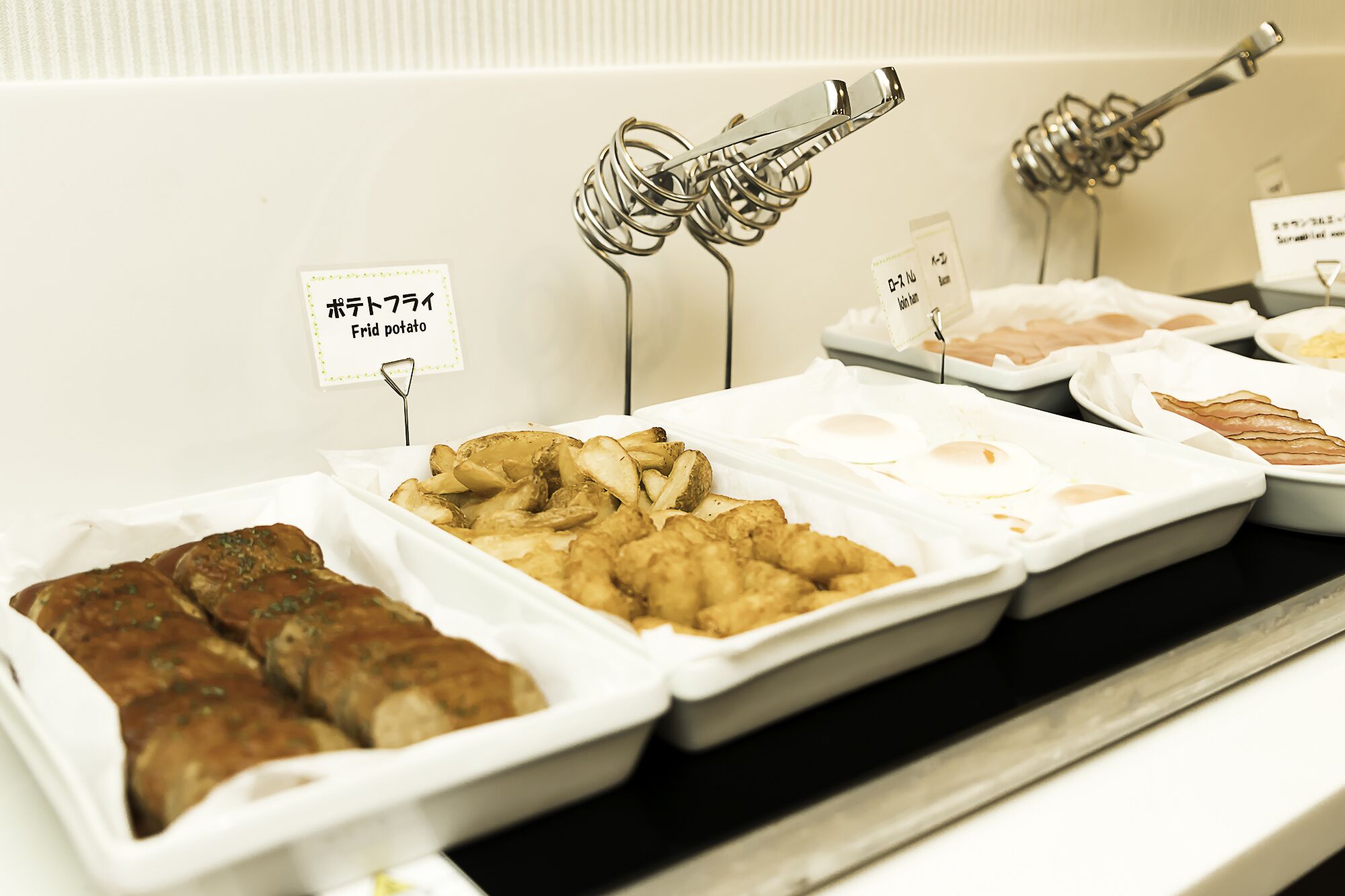 A buffet with various food items including fried potatoes, fried chicken, and other dishes.