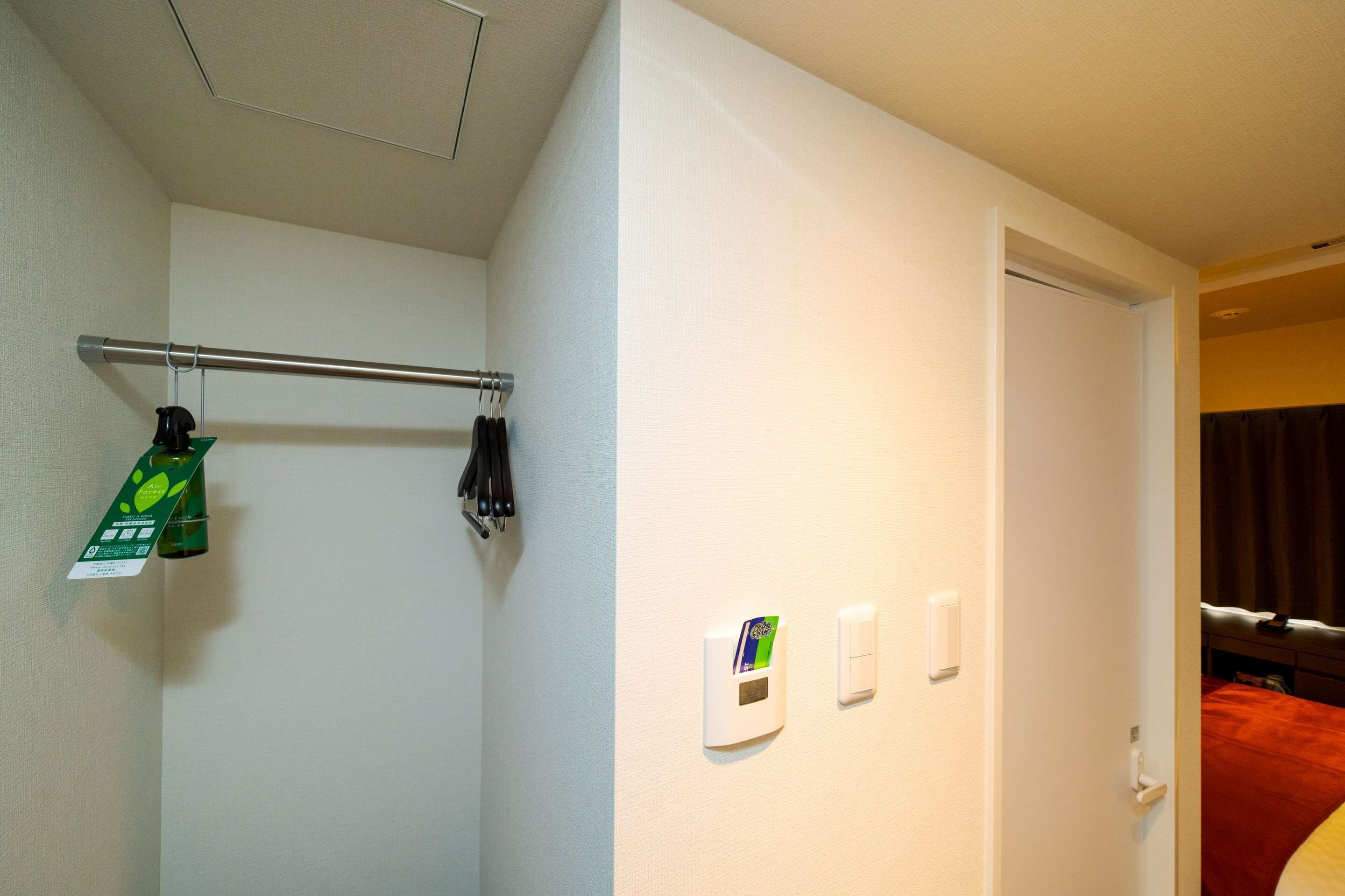 Quarto de hotel com cama, porta e interruptor de luz fixado na parede.