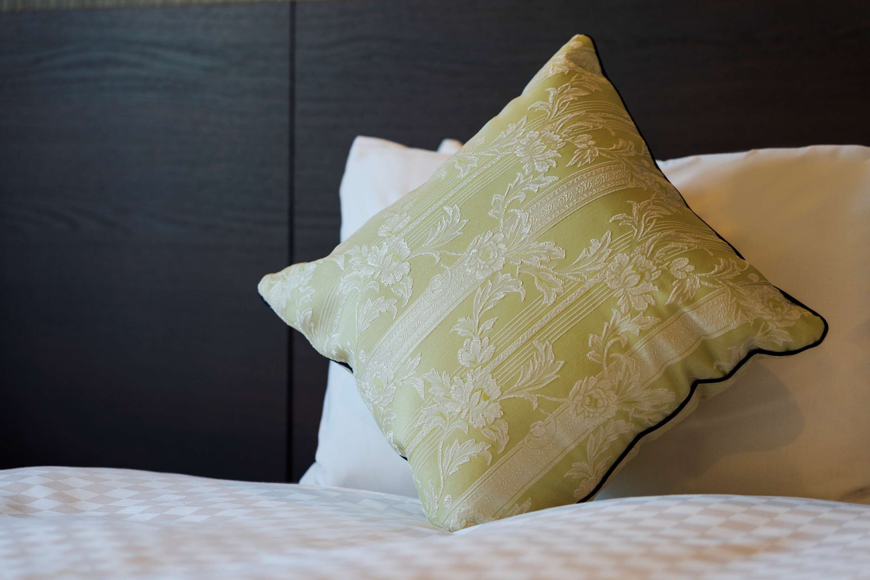 A bed with a patterned pillow and a dark headboard.
