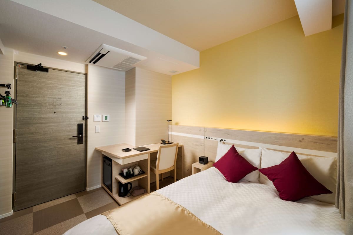 Een hotelkamer met een bed, een bureau, een stoel en een kledingkast.