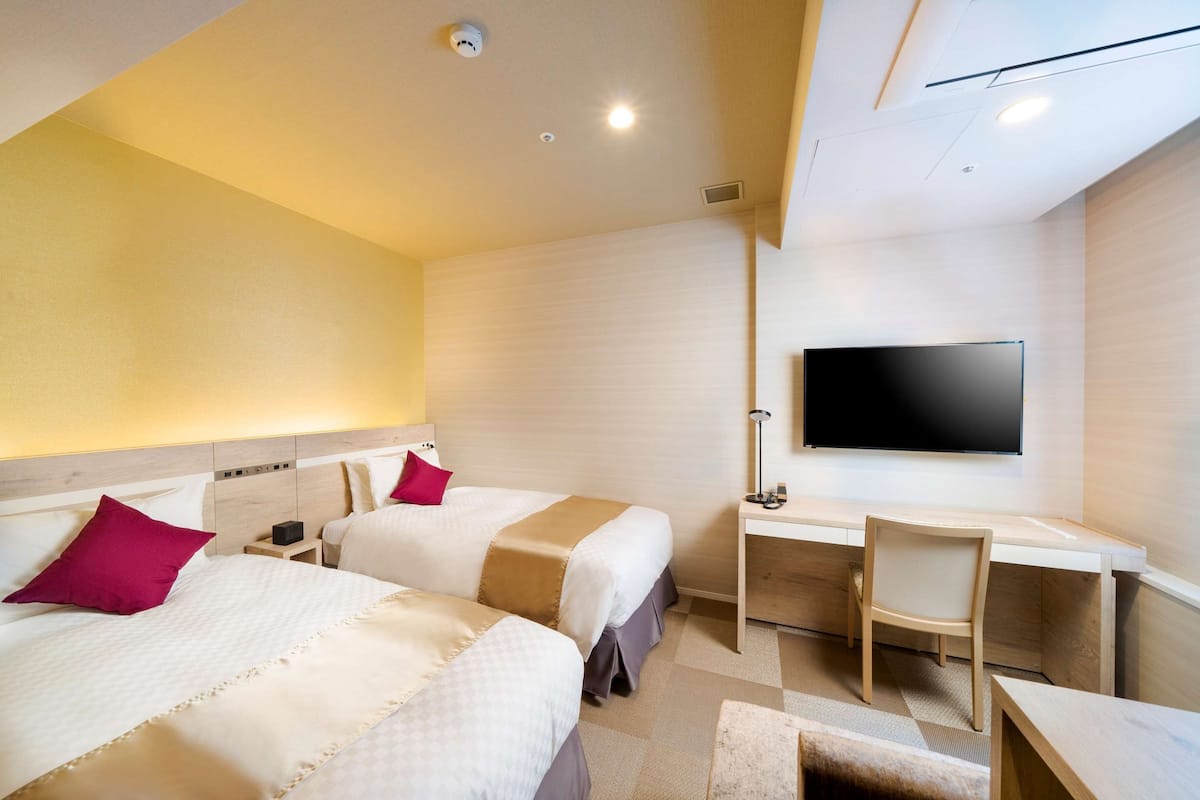 Een hotelkamer met twee bedden, een bureau, een stoel en een televisie.