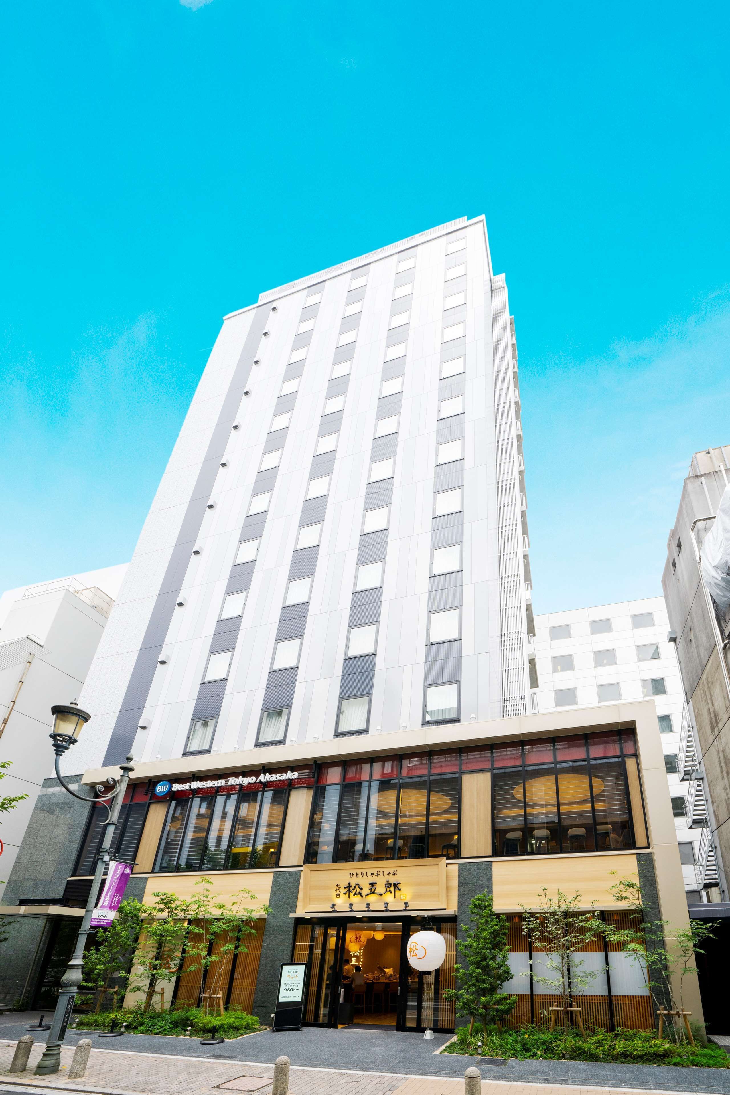 A tall building with a modern design, featuring a restaurant at the ground level with large windows and a sign in a foreign language.