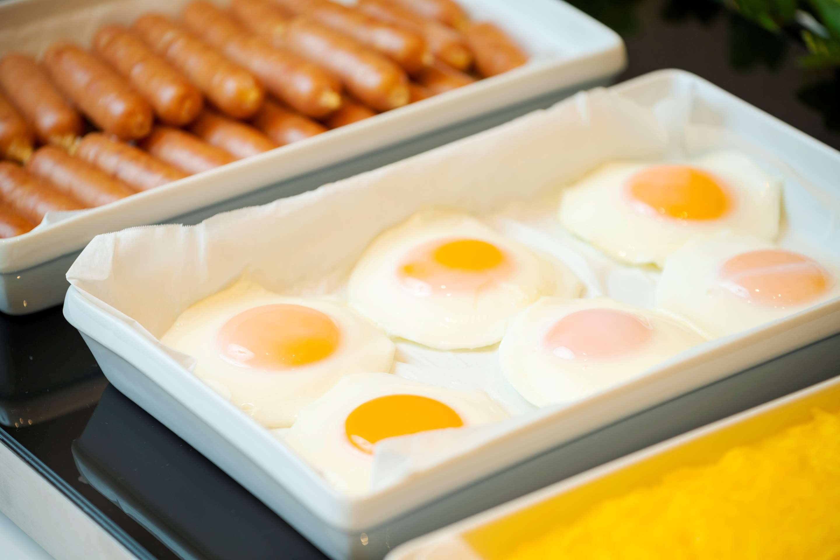 A tray of fried eggs and sausages on a table.