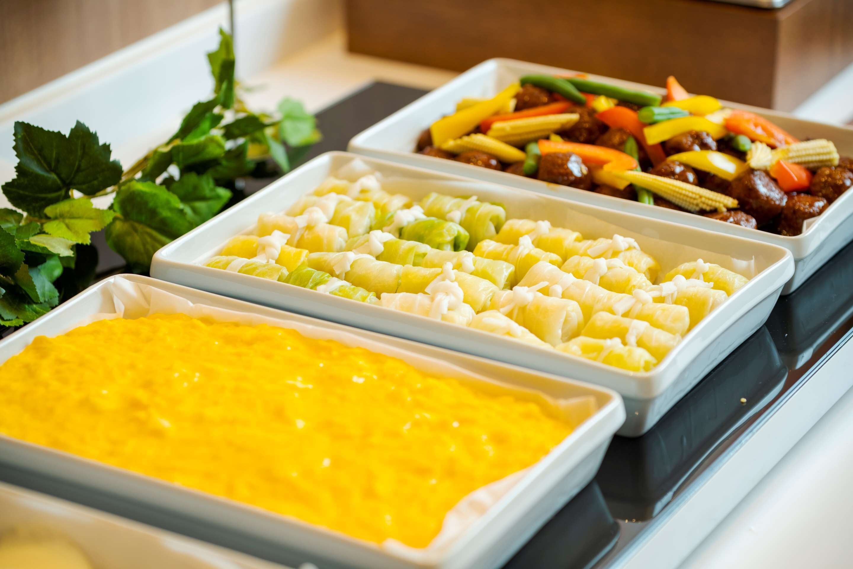 A buffet with various dishes including a yellow dip, a vegetable tray, and a meat dish.