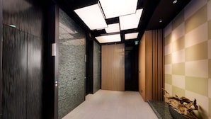 Een moderne liftinrichting met een geruit wandpaneel, een houten lambrisering en een centrale wand van houten latten.