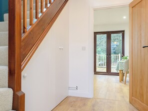 A staircase leading to a balcony with a wooden railing, a door with a handle, and a view of the outside.