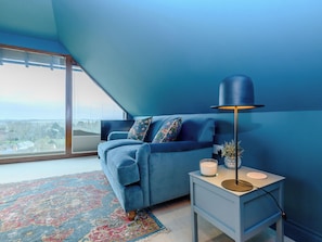A room with a blue sofa, a small side table with a lamp, and a large window with a view. - 1 bedroom accommodation in Wherwell (Wherwell)