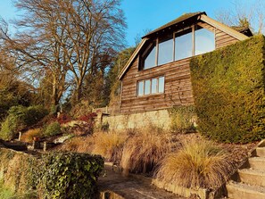 Une maison en bois avec un toit en pente, de grandes fenêtres et des fondations en pierre.