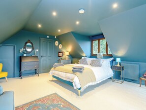 A bedroom with a bed, dresser, nightstand, lamp, and a window.