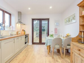 A kitchen with a dining area, wooden flooring, and a view through a glass door.