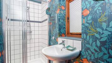 Une salle de bain avec une douche, un lavabo et un miroir.