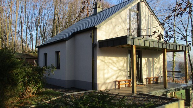 Ein modernes Haus mit Satteldach, einer überdachten Veranda und einem kleinen Garten.
