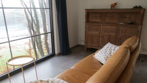 Ein Wohnzimmer mit einer braunen Ledersofa, einem kleinen runden Tisch und einer Holzkabine mit einer dekorativen Elefant.
