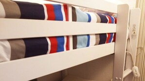 A bunk bed with striped bedding, a white headboard, and a power outlet on the side. - Singlin Home - Skiing, trekking, holiday home. (Valtournenche)