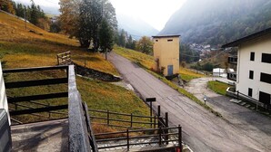 A rural road with a stone staircase leading down to a small building, surrounded by hills and sparse vegetation. - Singlin Home - Skiing, trekking, holiday home. (Valtournenche)