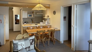 Una cocina compacta con una isla central, sillas de madera y una mesa de comedor.
