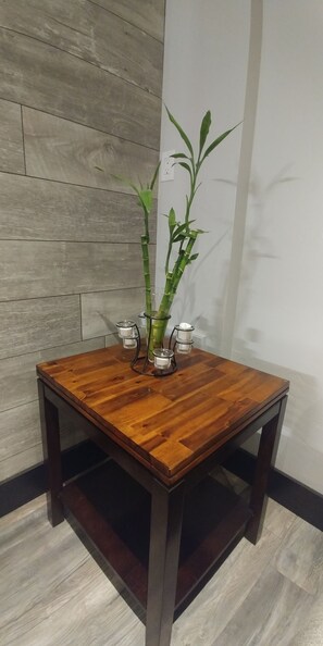 A stylish table with a bamboo plant and candle holders sits against a wood-textured paneling.