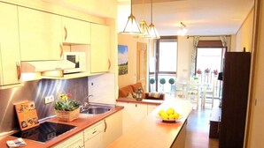 A modern kitchen with a central island, stainless steel appliances, and a view into the dining area. - Natural light, quiet, and in a great location (Madrid)