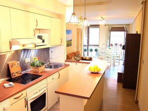 A modern kitchen with a central island, stainless steel appliances, and a view into the dining area. - Natural light, quiet, and in a great location (Madrid)