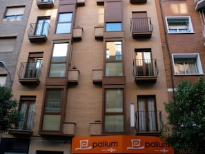 A multi-story building with balconies, windows, and a sign for 'palium.'