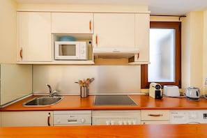Cocina compacta equipada con microondas, tostadora, hervidor y lavavajillas.