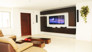 Un salon moderne avec un grand téléviseur à écran plat fixé au mur, un canapé, une table basse et une porte.