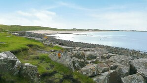 Eine Küstenlandschaft mit felsigem Gelände und einem Sandstrand.