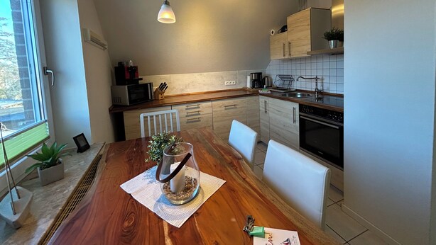 Una cocina moderna con armarios de madera, una mesa de comedor con sillas e iluminación colgante.