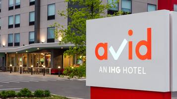 A sign for 'Avid IHG Hotel' with a modern building in the background.