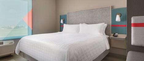 A hotel room with a large bed, bedside tables, a window, and a view.